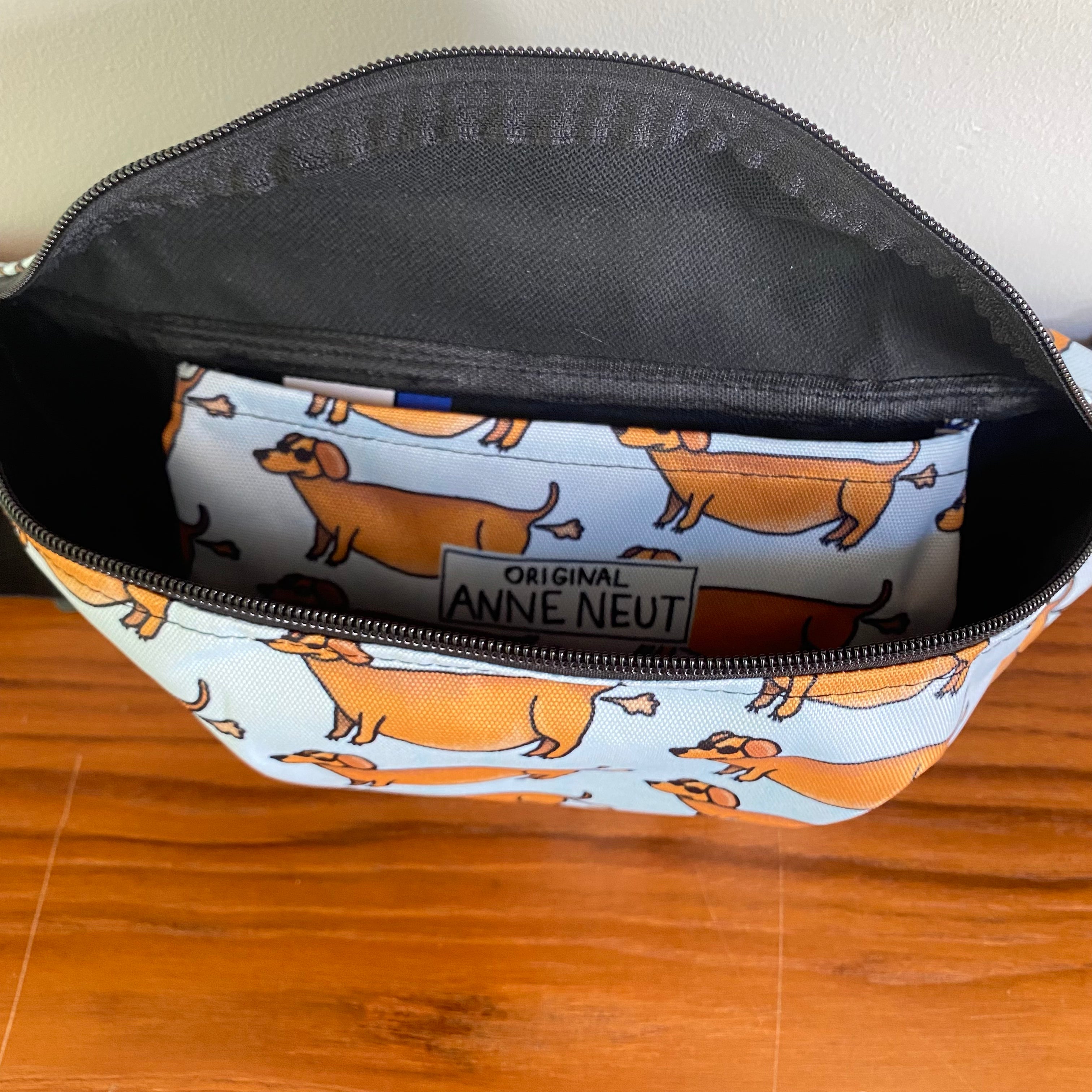 Fanny pack met tekening van teckels die scheetjes laten door Anne Neuteboom cabaretier Anne Neut Boetiek
