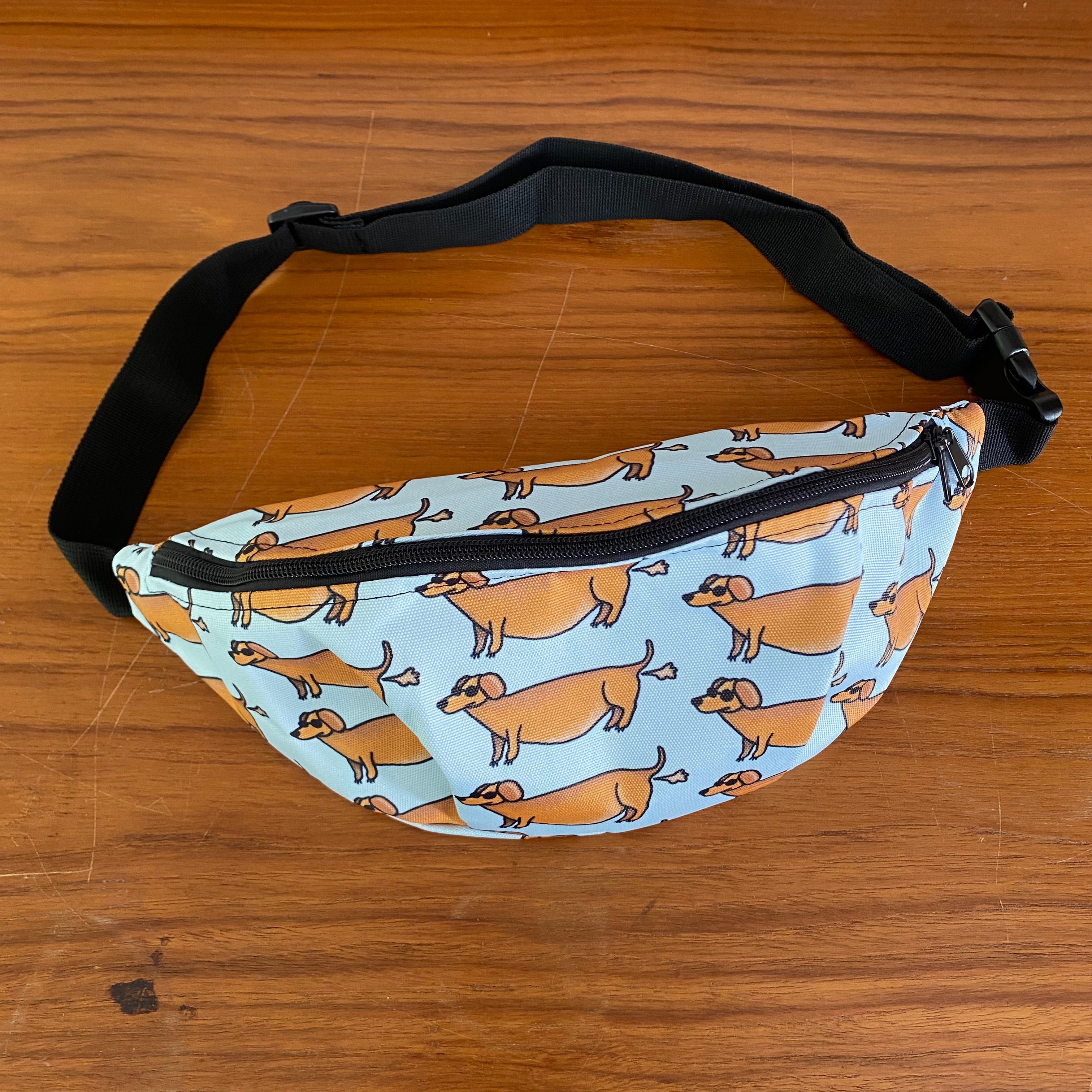 Fanny pack met tekening van teckels die scheetjes laten door Anne Neuteboom cabaretier Anne Neut Boetiek