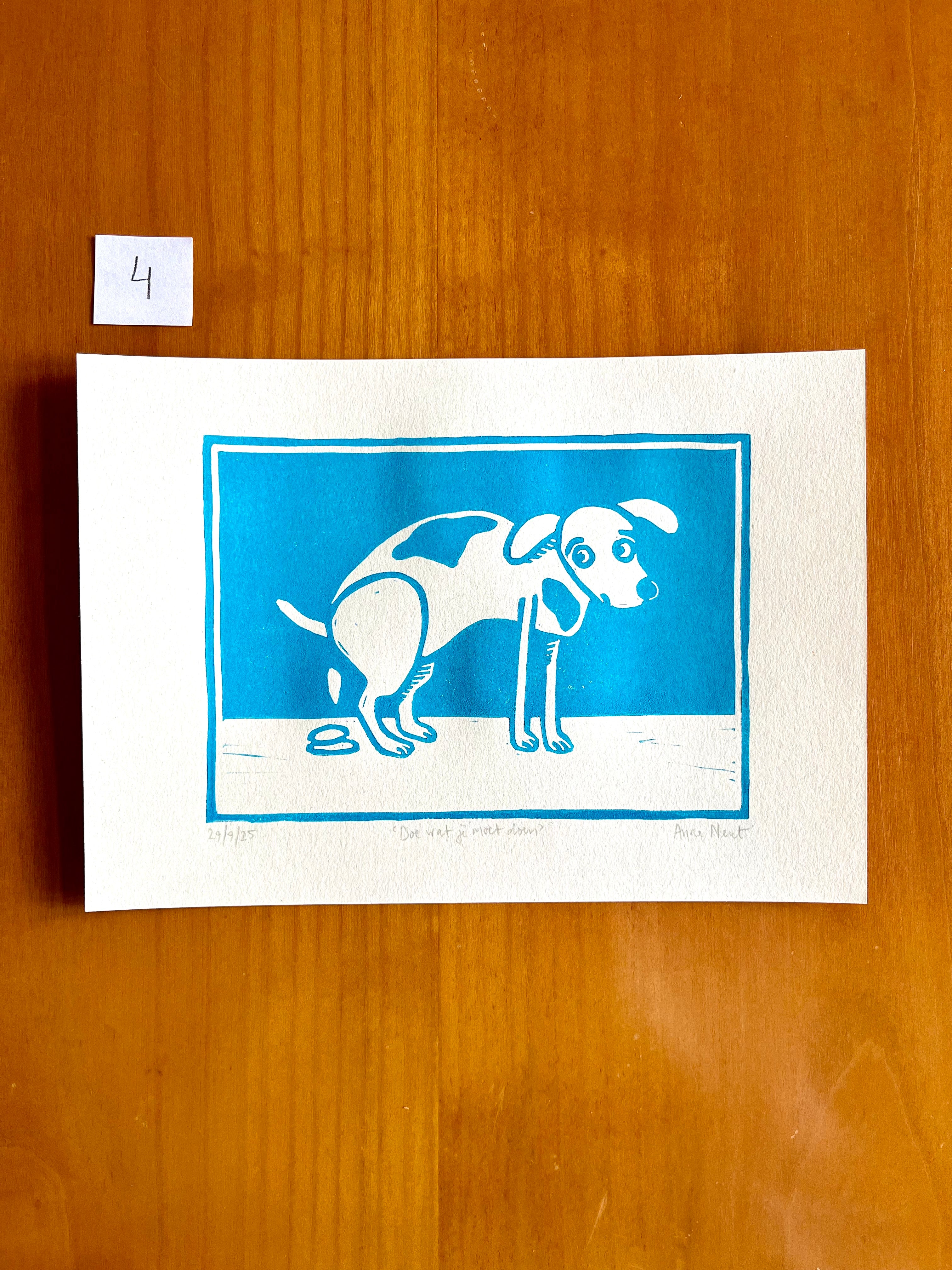 Linoprint van tekening van poepende hond door Anne Neuteboom cabaretier Anne Neut Boetiek