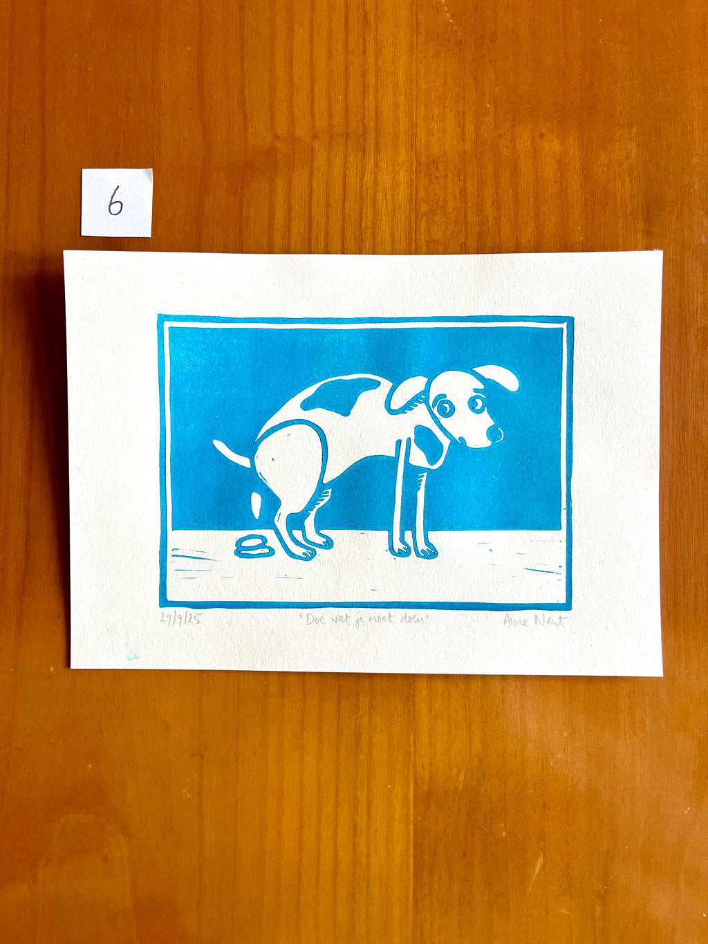 Linoprint van tekening van poepende hond door Anne Neuteboom cabaretier Anne Neut Boetiek