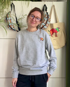 Sweater met borduurwerk van tekening van poepende hond door Anne Neuteboom cabaretier in Anne Neut Boetiek