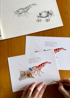 Digitale aquarel tekening van een garnaal die de krant leest door Anne Neuteboom cabaretier Anne Neut Boetiek