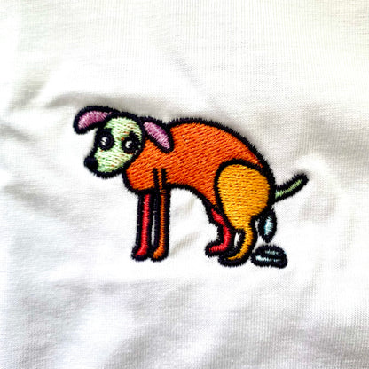 Shirt met borduurwerk van tekening van poepende hond door Anne Neuteboom cabaretier in Anne Neut Boetiek