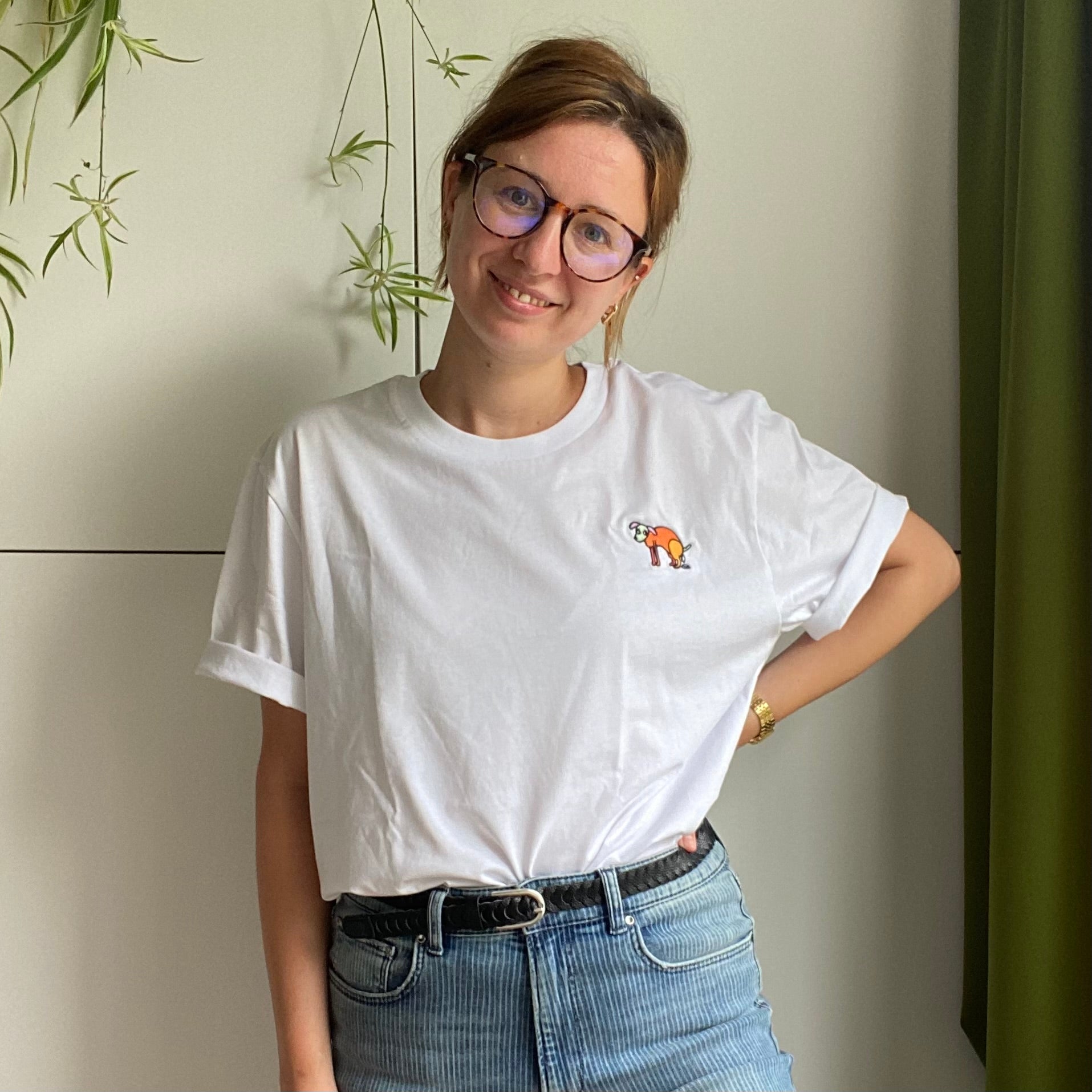 Shirt met borduurwerk van tekening van poepende hond door Anne Neuteboom cabaretier in Anne Neut Boetiek