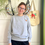 Sweater met borduurwerk van tekening van poepende hond door Anne Neuteboom cabaretier in Anne Neut Boetiek