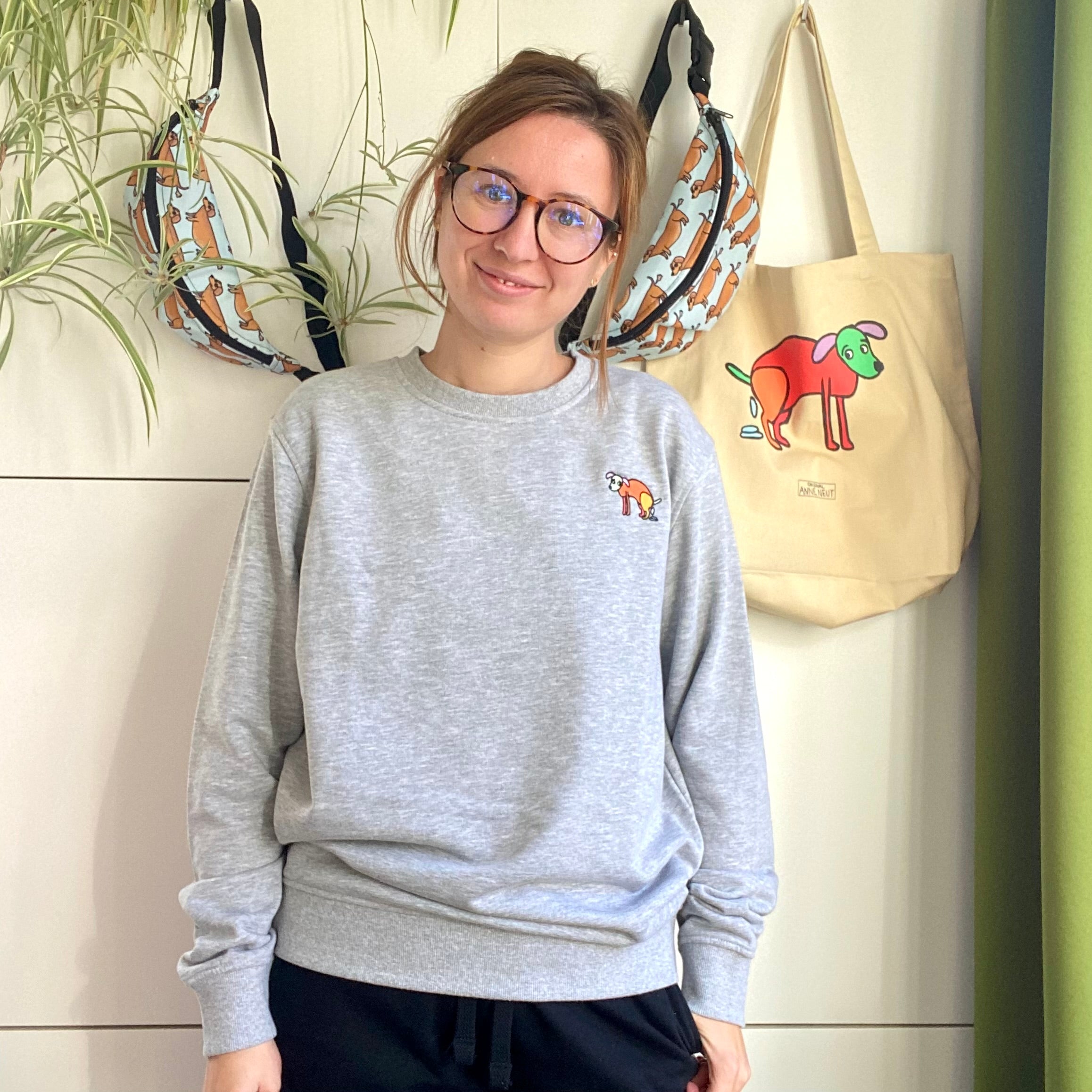 Sweater met borduurwerk van tekening van poepende hond door Anne Neuteboom cabaretier in Anne Neut Boetiek