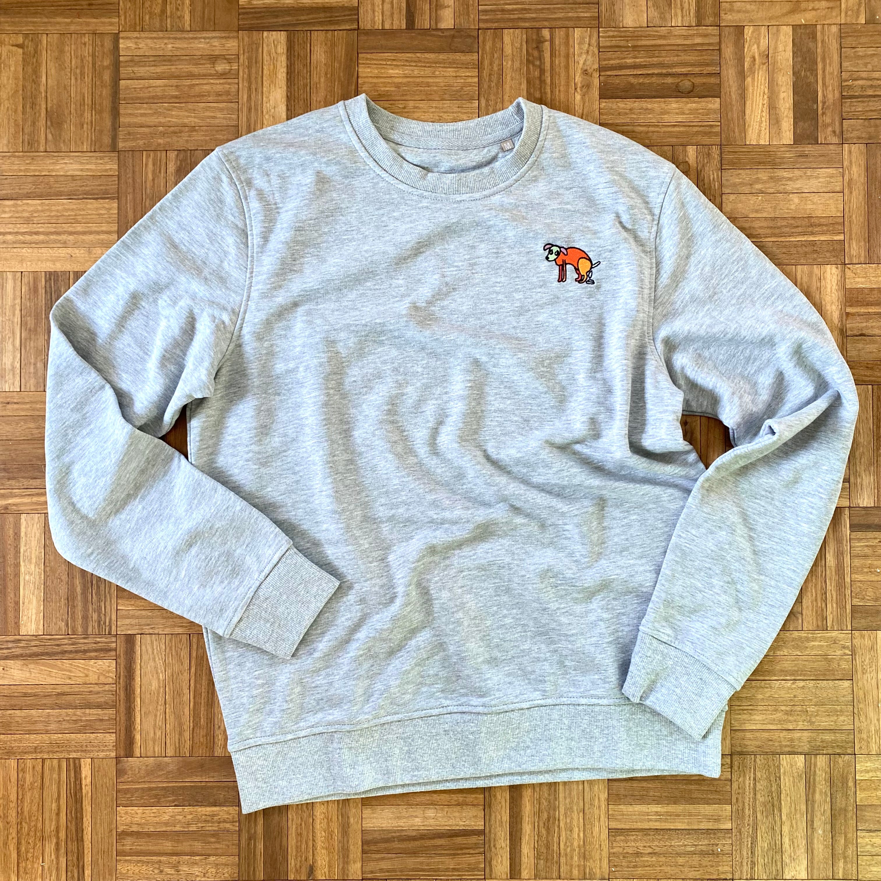 Sweater met borduurwerk van tekening van poepende hond door Anne Neuteboom cabaretier in Anne Neut Boetiek