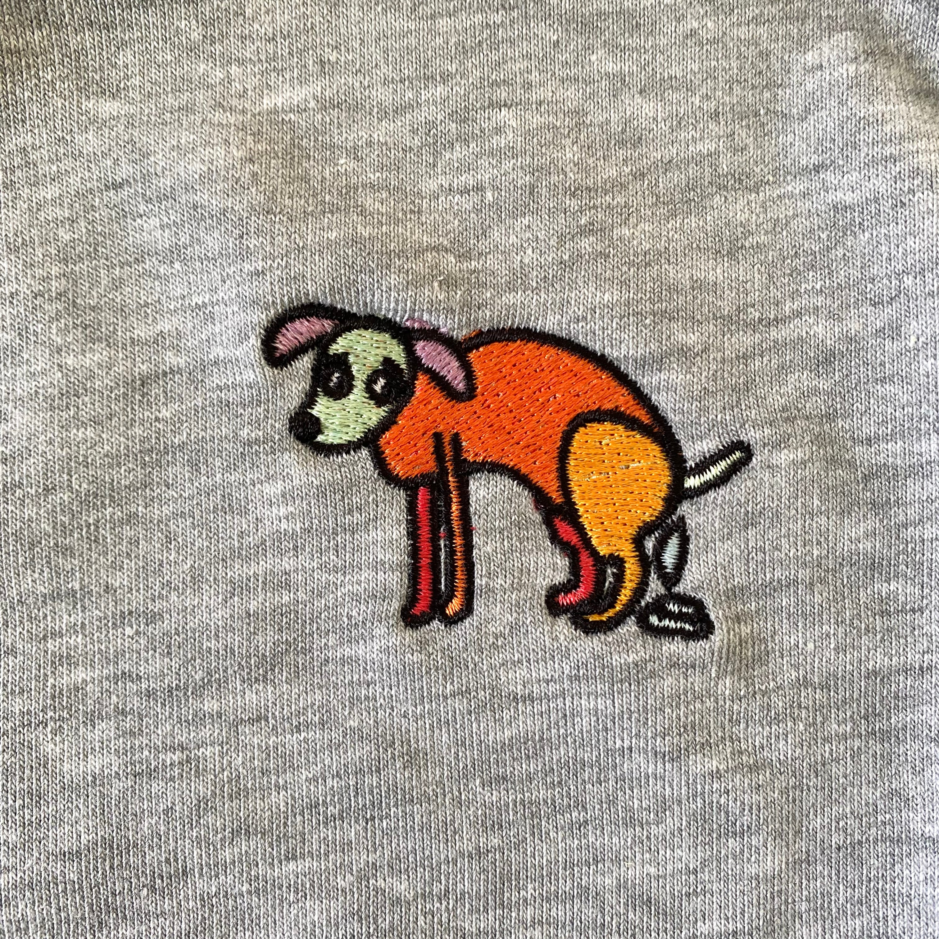 Sweater met borduurwerk van tekening van poepende hond door Anne Neuteboom cabaretier in Anne Neut Boetiek